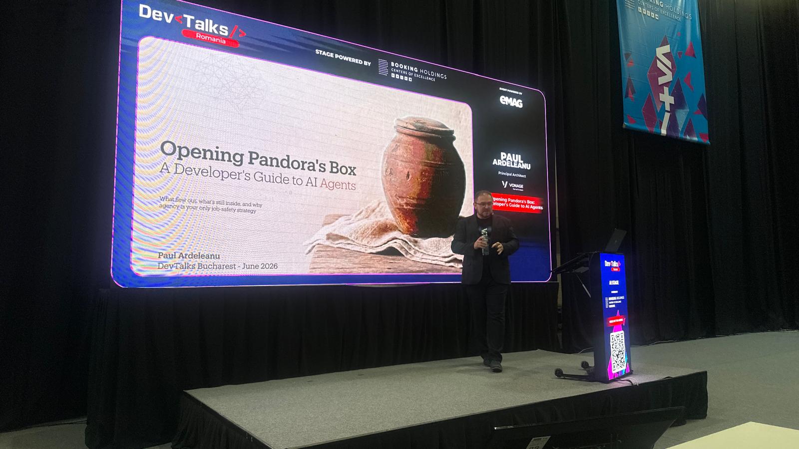 Paul Ardeleanu on stage at DevTalks Romania with the Opening Pandora's Box title slide on the big screen behind him.